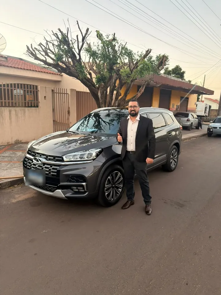 Cliente de terno ao lado do SUV cinza que comprou na LV, fazendo sinal de positivo