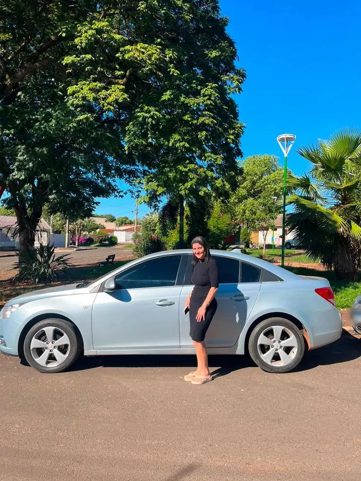 Cliente sorrindo encostada no sedã prata que comprou na LV